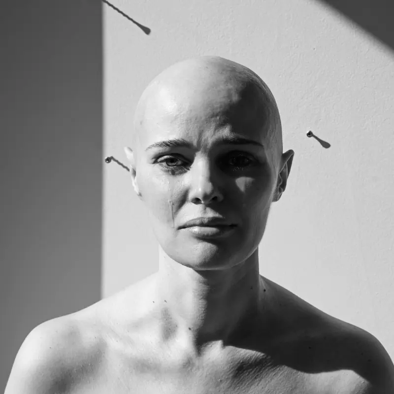 Czarno-biały portret kobiety z ogoloną głową, oświetlonej ostrym bocznym światłem. Fotografia „Wygnanie” Nadyi Mitskevich i Katyi Konsulovej, nagrodzona I nagrodą XXX edycji.